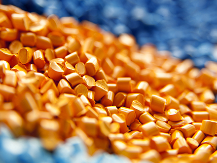 Nahaufnahme von gehäckseltem orangefarbenen und blauem Kunststoffgranulat
